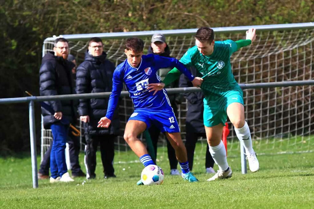 Mewan Ali (li., Eidertal) gegen Tim Mordhorst (Klausdorf). Im Hintergrund prominenter Besuch aus der Regionalliga mit Nicola Soranno (Trainer Kilia Kiel). Spielerbeobachtung? © 2024 Ismail Yesilyurt