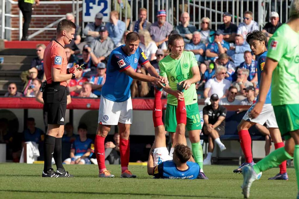 Benedikt Pichler (Holstein Kiel) wird von den beiden Patricks behandelt, links Erras und rechts Wimmer. © 2024 Ismail Yesilyurt