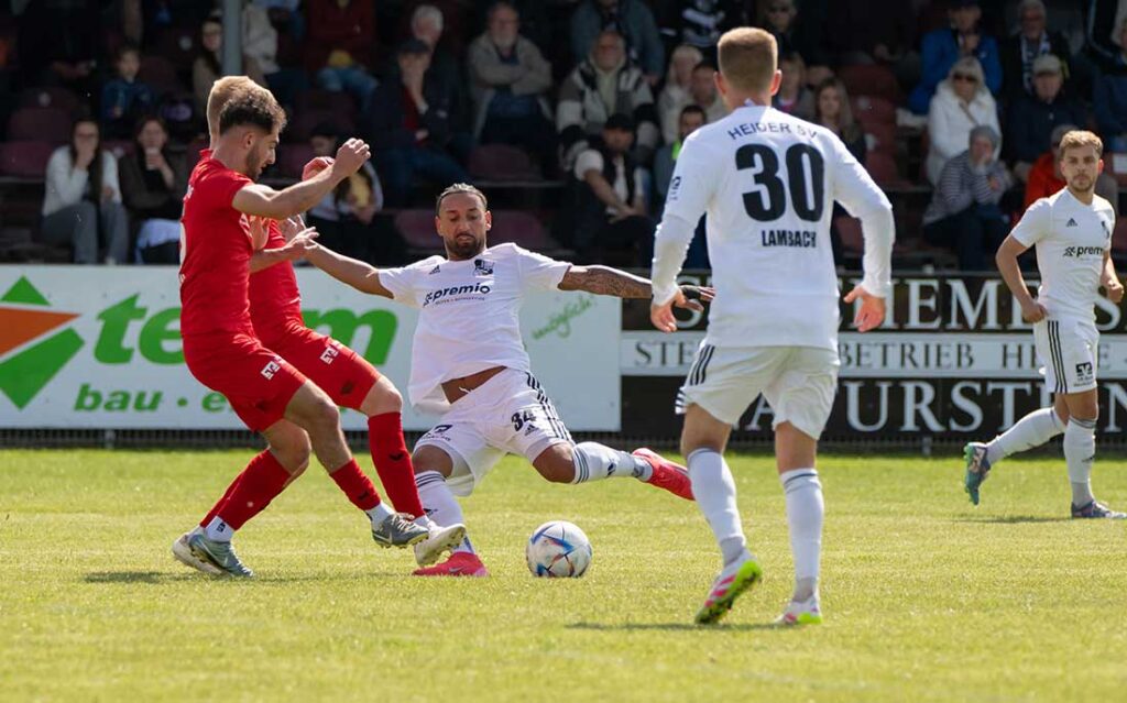 Azat Selcuk (Heider SV) kommt vor Raghib Hasan (TSB Flensburg) und Henrik Fleige (vedeckt) an den Ball. © 2025 Volker Schlichting