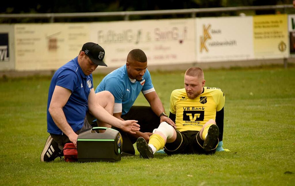 Keeper Eric Kühl (TuS Jevenstedt) muss behandelt werden. Auch Emanuel Amoako von Inter Türkspor hilft mit. © 2025 Olaf Wegerich
