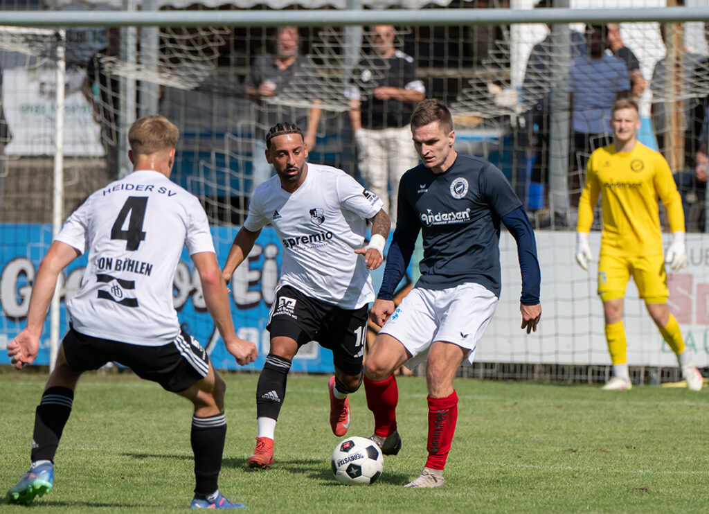 Björn Laß (TSV Nordmark Satrup) gegen tarek von Böhlen (li.) und Azat Selcuk (Heider SV). © 2025 Volker Schlichting