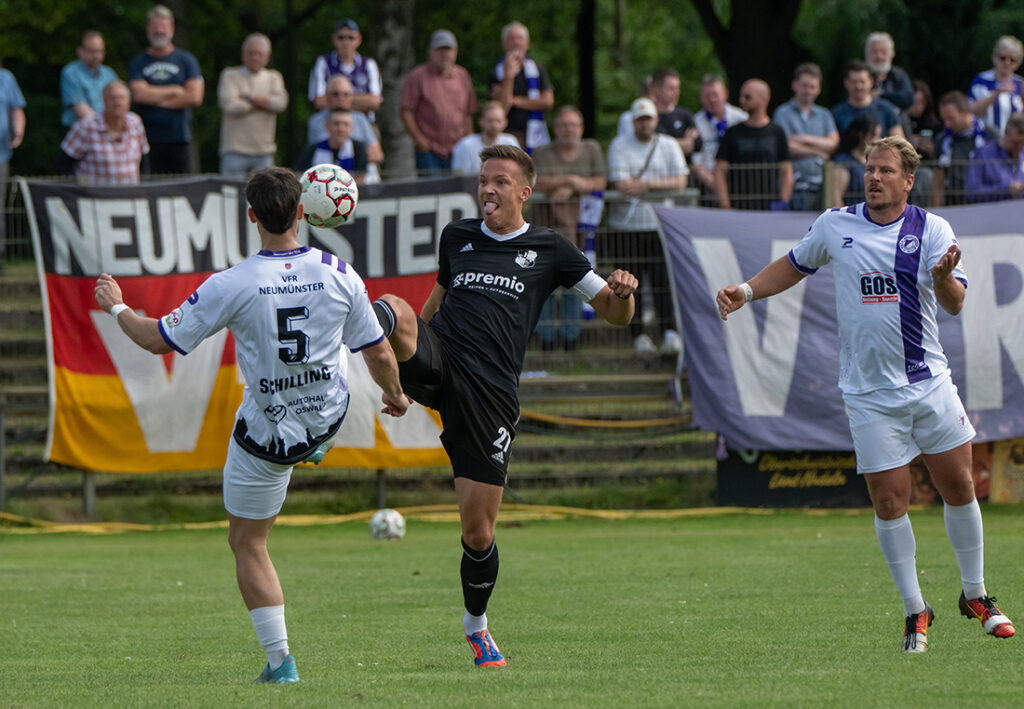 Jonah Gieseler (Heider SV) im Zweikampf mit Tom Schilling. Rechts Christopher Kramer (VfR Neumünster). © 2025 Volker Schlichting