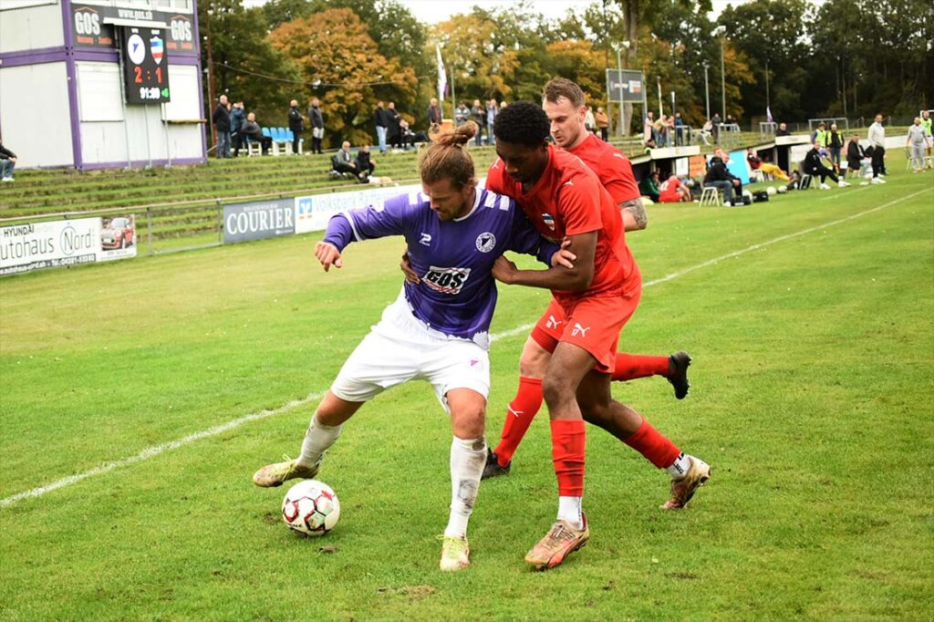 Kevin Schulz (VfR Neumünster) behauptet den Ball gegen Denzel Imasün und Andre Volkers (hinten, Inter Türkspor Kiel). © 2025 Olaf Wegerich