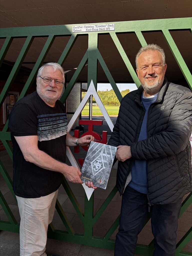 Autor Wolfgang Reimers (links) übergibt dem Vereinsvorsitzenden Tobias Dittmann das erste Buch der Holtenauer Fußballchronik. Fotografin Doris Reimers