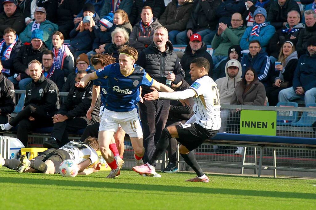 Jonas Therkelsen (Holstein Kiel) gegen Jan Gymerah (SV Elversberg) vor den Augen von Holstein-Trainer Tim Walter. © 2026 Ismail Yesilyurt