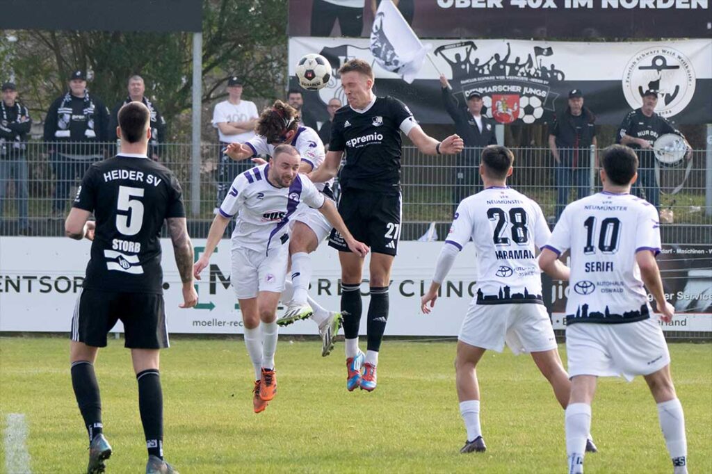 Jonah Gieseler (Heider SV) gewinnt den Kopfball gegen Christoph Kahlcke (vorne) und Jan Lippegaus (VfR Neumünster). © 2026 Volker Schlichting