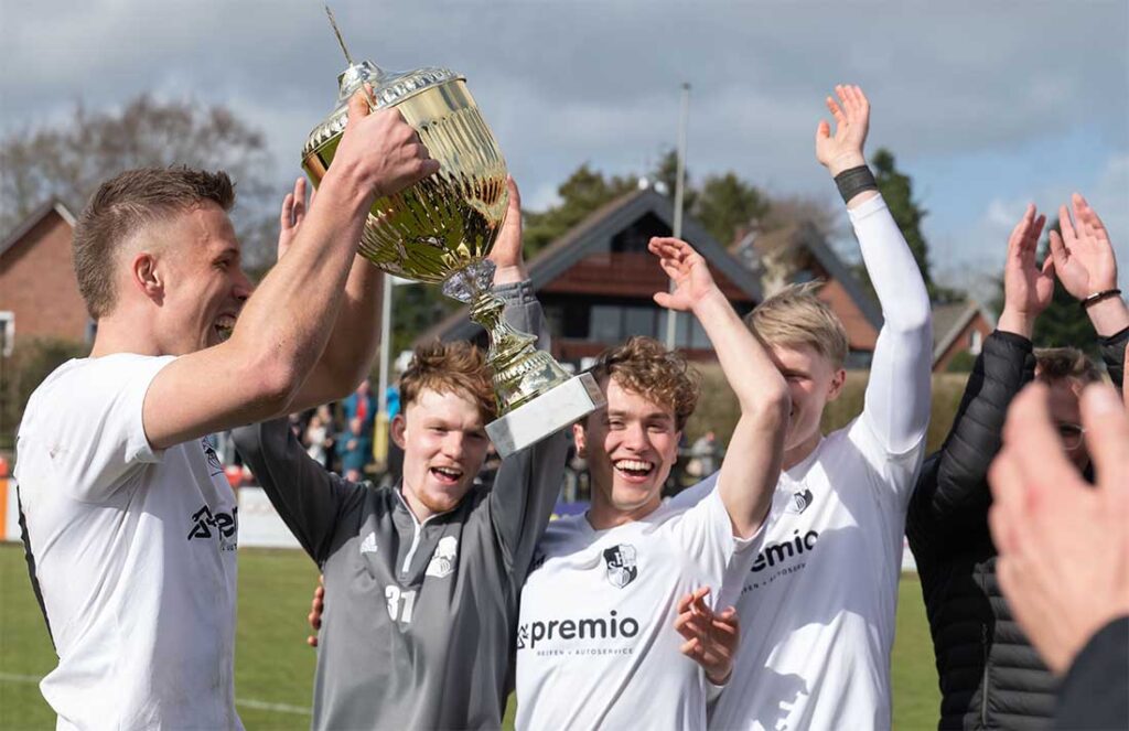 Kapitän Jonah Gieseler (Heider SV) stemmt den Kreispokal nach dem Sieg gegen die SG Geest in die Höhe. © 2026 Volker Schlichting