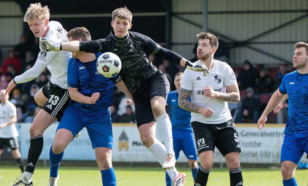 Rechter Haken von Keeper Paul Maron (SG Geest) an seinen Kapitän David Freund. Hendrik Fleige (li.) und Patrick Storb (Heider SV) halten sich außer Reichweite auf. © 2026 Volker Schlichting