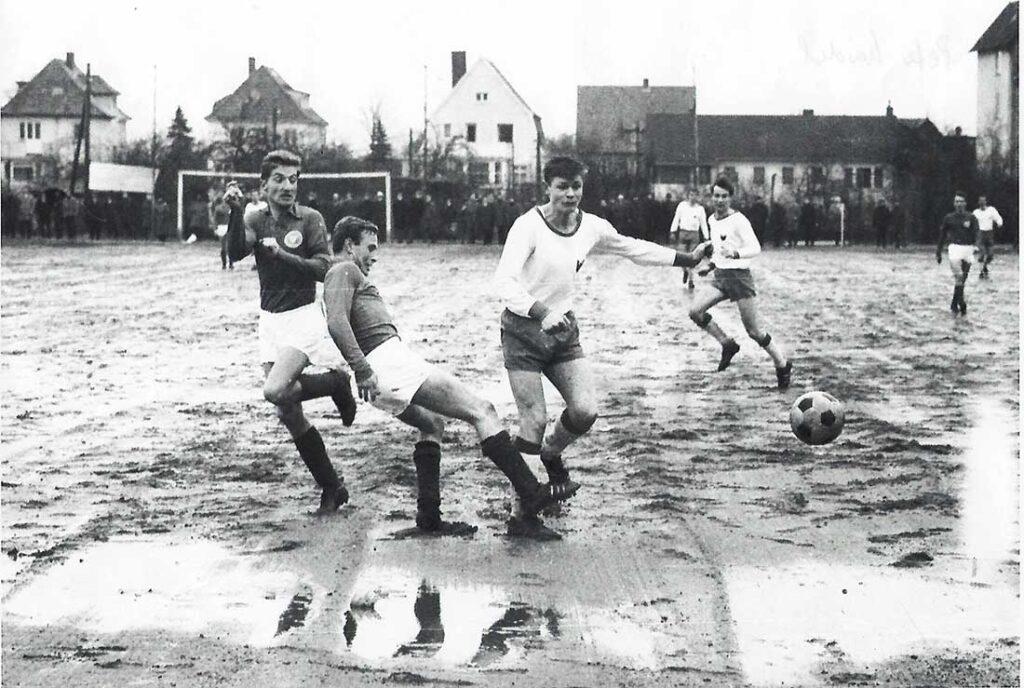 m April 1966 gastierte Phönix Lübeck mit dem späteren Nationalspieler Peter Nogly bei Holsteins Amateuren auf dem Fögeplatz. Blickrichtung Projensdorfer Straße, das Stadion ist nicht mehr im Bild, liegt aber rechts. Links stehend Holsteins Peter Kardel.